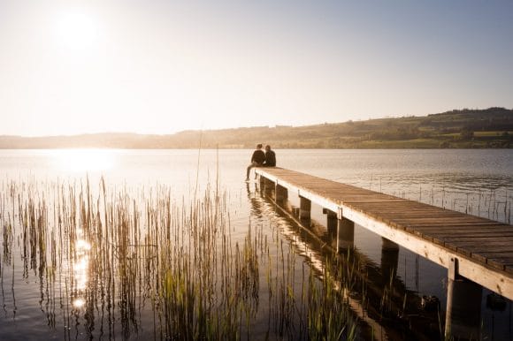 Couple sitting on pier at lake