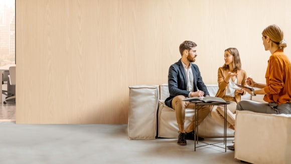 Ein Mann und eine Frau besprechen finanzielle Optionen mit einem Strategen in einem Bürogebäude.