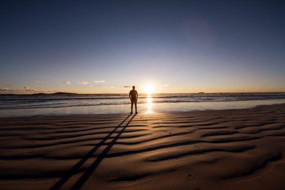 Man standing on beach looking at the sunset