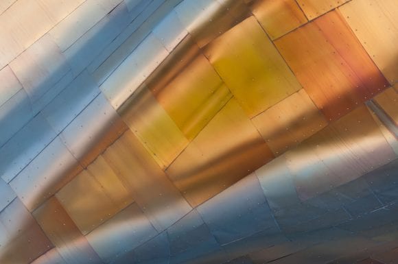 Abstract metallic texture with warm gold reflections and a polished, flowing surface.