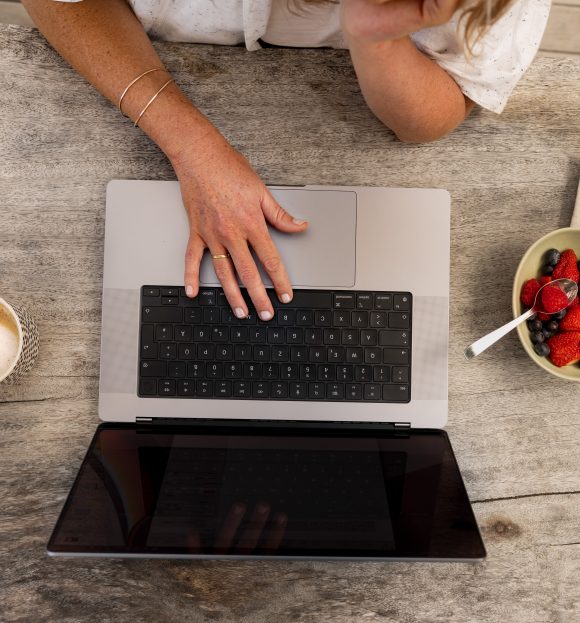 Top-down view of a person’s hands typing on a computer.