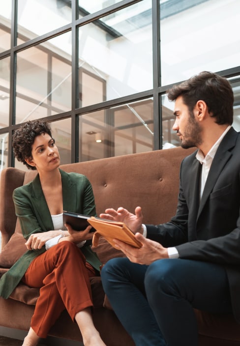 Two people sitting on a couch in a corporate office discussing 