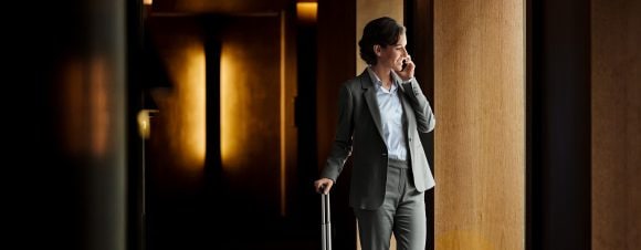 Businesswoman talking on phone in hotel corridor