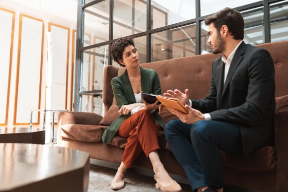 Two people in discussion in a office sitting on a sofa 