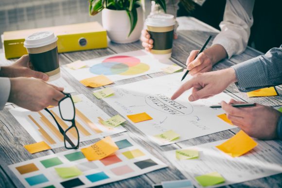 Une réunion de brainstorming entre un groupe de collègues, avec un bureau couvert de notes et de diagrammes.