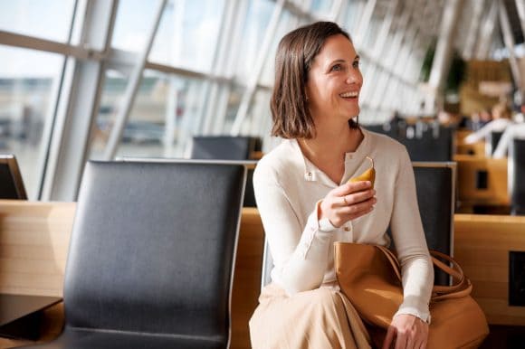 Eine Frau sitzt am Flughafen und hält eine Birne in der Hand.