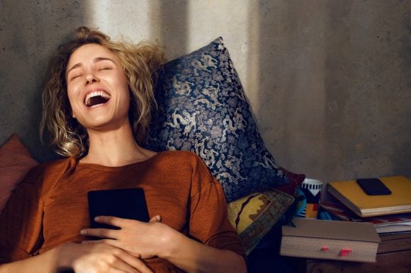 Young woman with e-book reader laughing