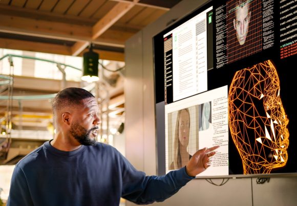 Mann, der ein KI-Seminar leitet und auf einen Screen zeigt.
