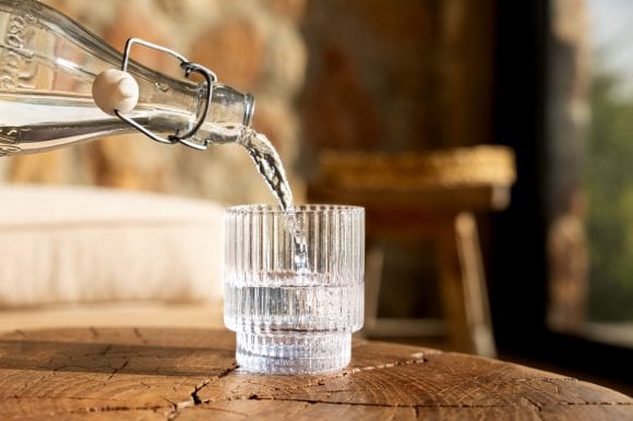 Wasser wird aus Wasserflasche in Glas eingeschenkt.