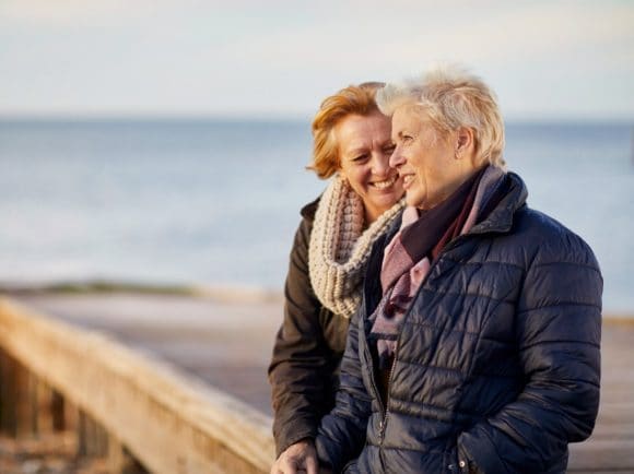 Two women laughing and talking by the sea.