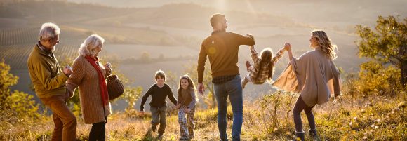 Grosseltern schauen auf die Familie ihrer Tochter mit zwei Kindern beim Wandern in den Bergen.