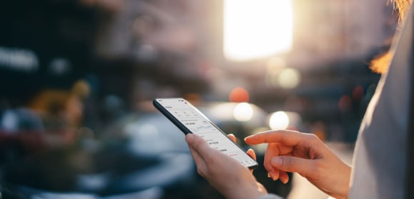Woman reading financial trading data on smartphone in street