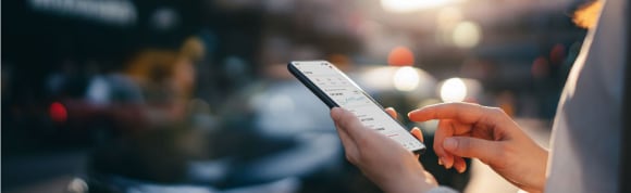 Woman reading financial trading data on smartphone in street
