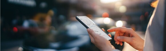 Woman reading financial trading data on smartphone in street