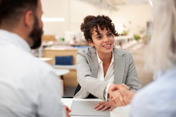 Front-facing view of a bank employee who is shaking hands with clients after a meeting.