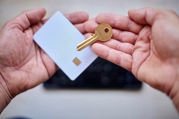 Hands of an adult holding a payment card and a key.