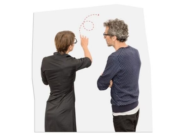 Two people stand next to a wall, drawing something.
