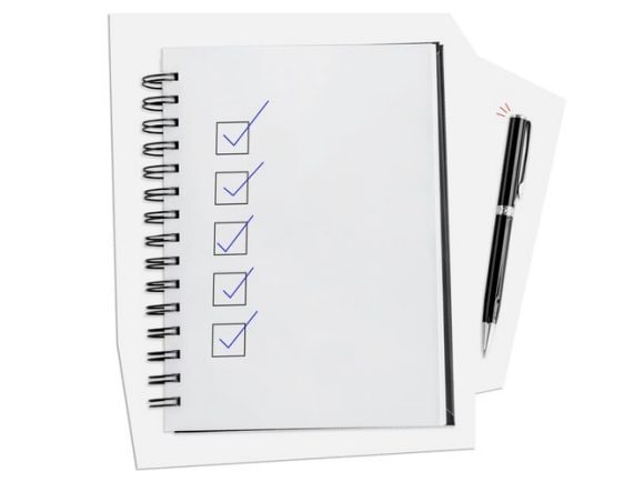 A spiral-bound notebook with a completed checklist and a black pen next to it.