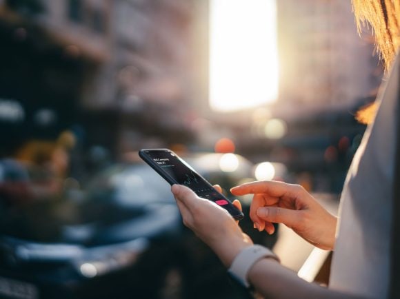 A woman reading is financial data on a smartphone in a street