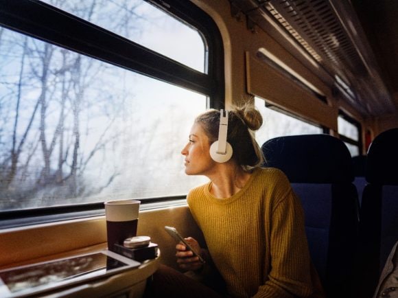 A woman on a commuter train listening to music with headphones