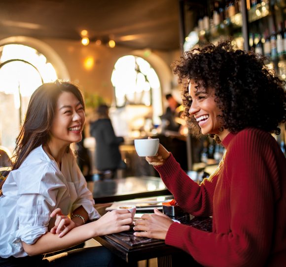 Two women talking and laughing in a café.