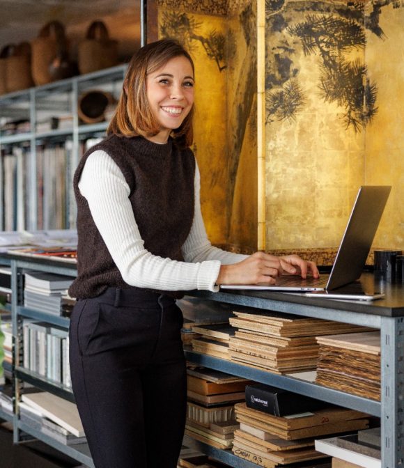Young woman standing at a laptop in a studio.