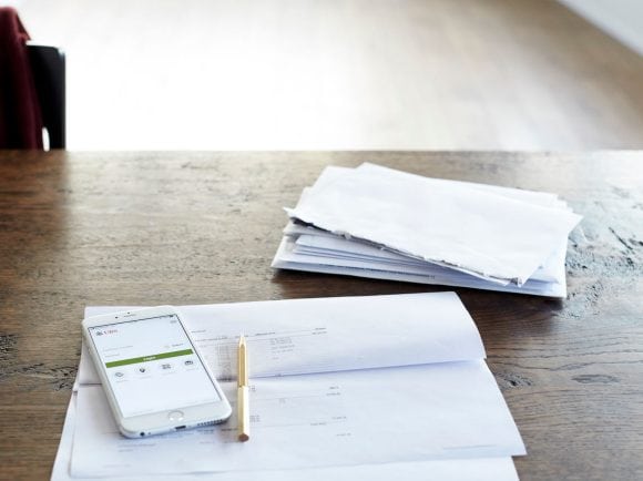 A smartphone with the UBS app open lies on top of an opened letter.