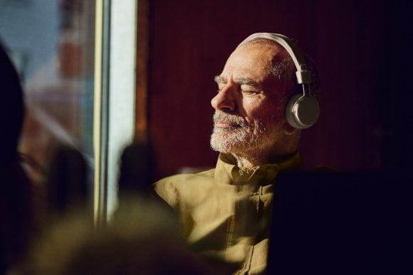 An older man is relaxing and listening to music with headphones.