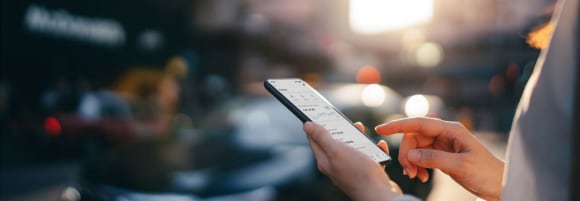 Woman reading financial trading data on smartphone in street
