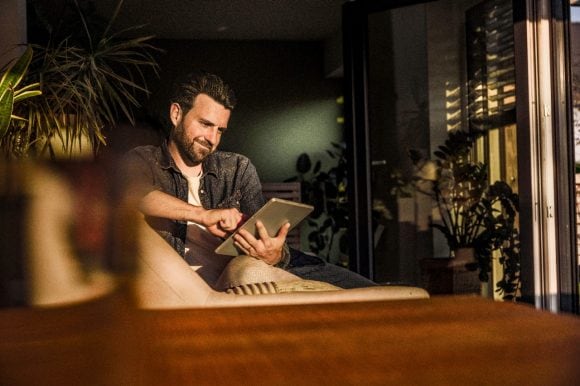 Man with tablet computer at home smiling