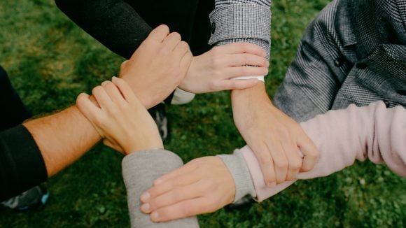 Four hands holding each other to form a square