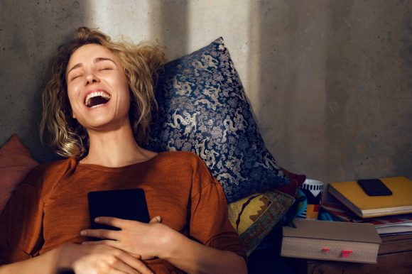 Young woman with e-book reader laughing
