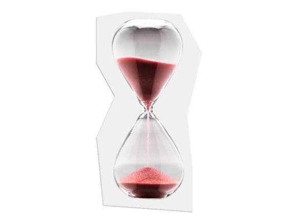 Sablier transparent avec du sable rouge sur fond clair, symbolisant le temps qui passe et l’importance de planifier bien à l’avance.