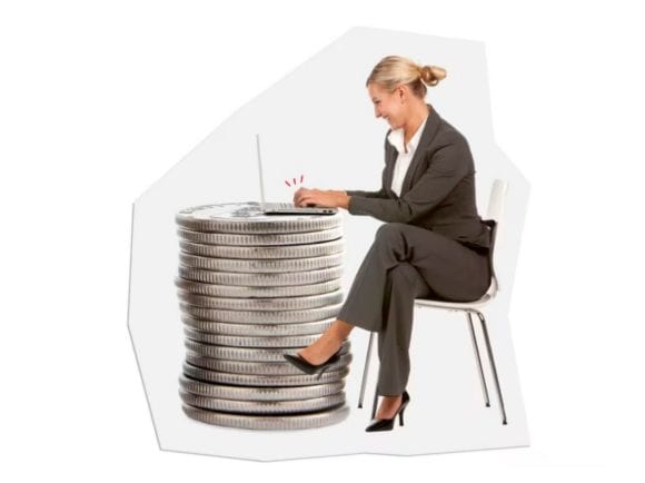 Une femme devant son ordinateur portable, posé sur une pile de pièces.
