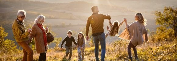 Des grands-parents regardent leur fille, leur gendre et leurs deux petits-enfants lors d’une randonnée en famille à la montagne.