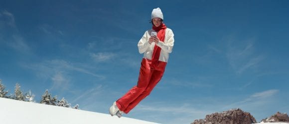 Jumping girl holding phone on snow