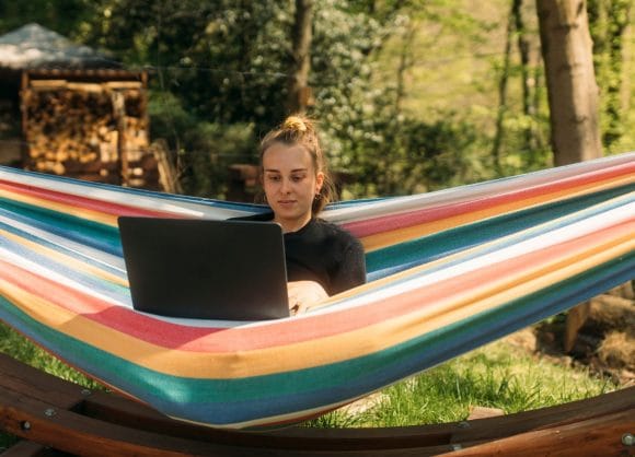 Fille dans un hamac travaillant sur un ordinateur portable