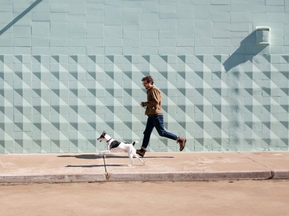 Un uomo corre sul marciapiede con il suo cane.