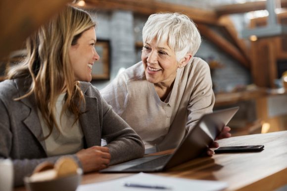 Una donna anziana è seduta comodamente sul divano e usa laptop e carta di credito per fare un acquisto online sicuro