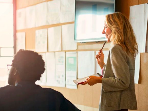 A woman and a man are looking at a tablet together in an office.