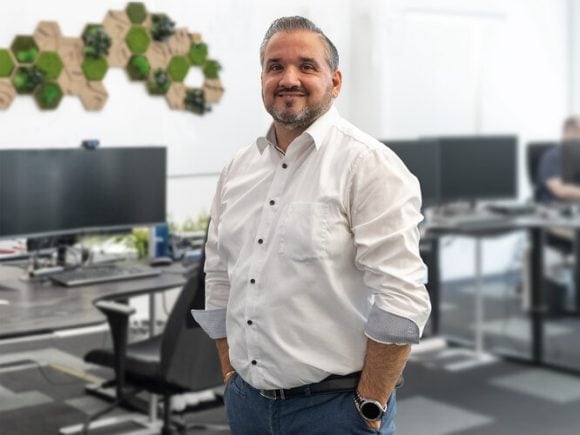 José Lopez in a white shirt with his office in the background.