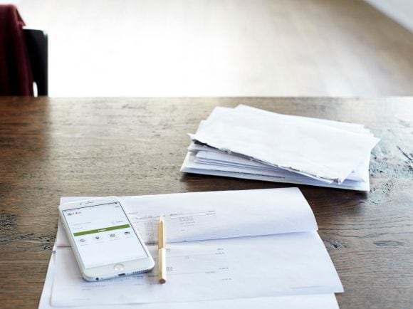 A smartphone with the UBS app open lies on top of an opened letter.