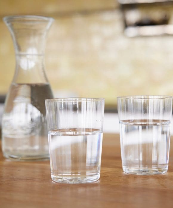 Tavolo con caraffa d’acqua e due bicchieri d’acqua pieni