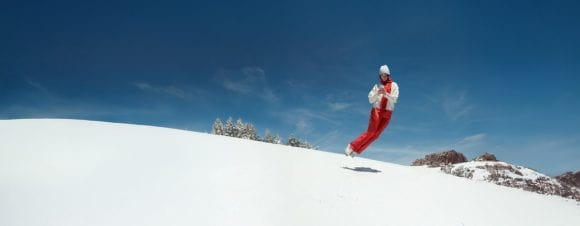 Ragazza che salta con il telefono sulla neve