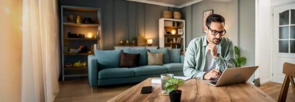 Man in glasses working on a laptop at home