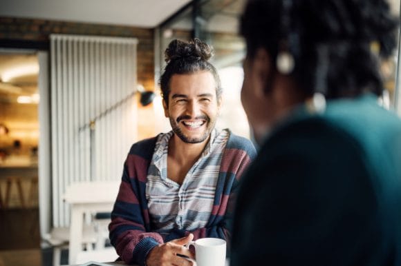 Due giovani amici che fanno una pausa caffè e chiacchierano felicemente.