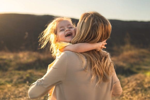 Una madre che abbraccia la figlia mentre camminano felicemente in montagna.
