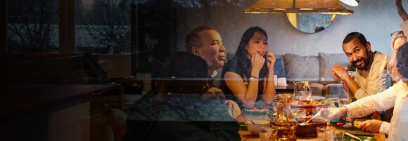 Famiglia multigenerazionale durante la cena, vista attraverso una finestra