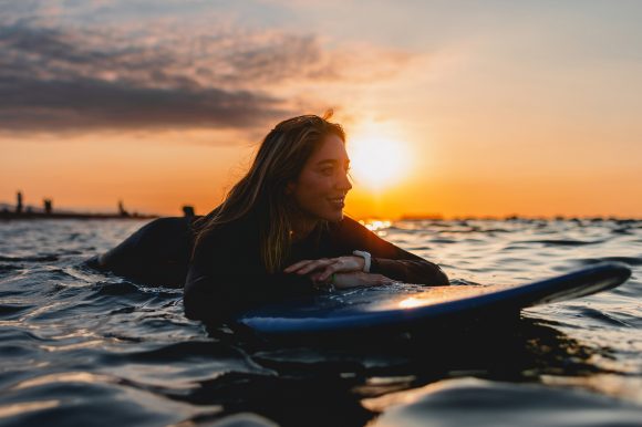 : Una donna sdraiata su una tavola da stand up paddle al tramonto