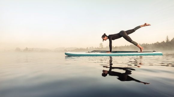 Woman doing yoga on surf board